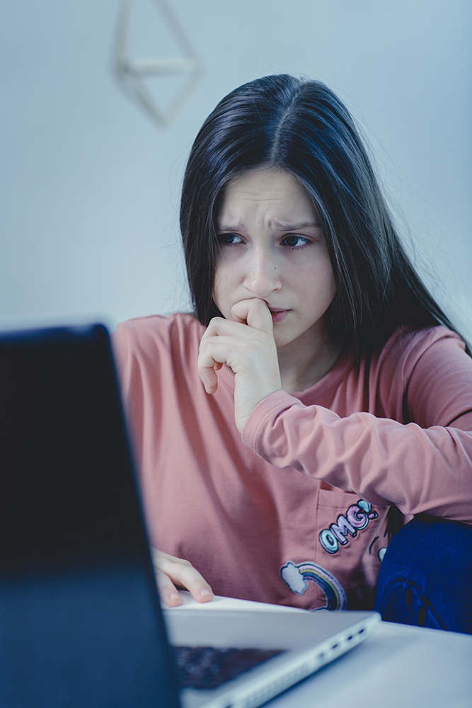 sad and scared female teenager with computer laptop suffering cyberbullying and harassment being online feeling desperate and humiliated in cyber bullying concept